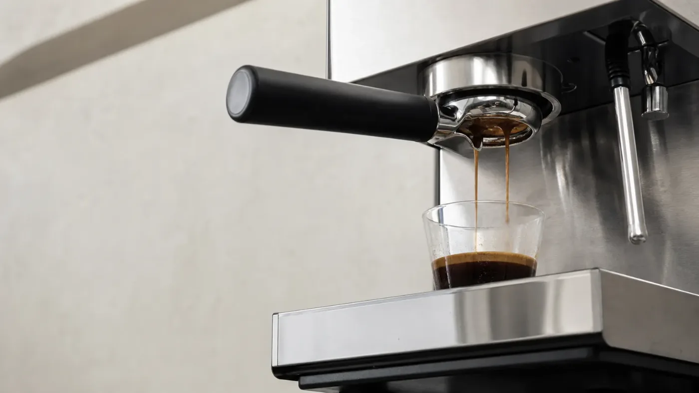Detalj profesionalnog espresso aparata tokom ekstrakcije